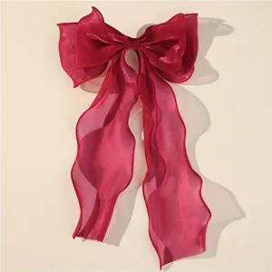 Detail view of a large magenta sheer mesh bow hair clip with long ribbons for elegant styles.
