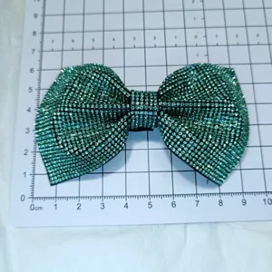 Detailed view of green rhinestone bow patch, sparkling diamond DIY shoe and hair accessory.