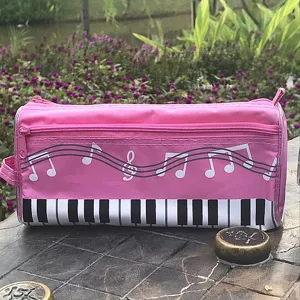 Estuche de lona rosa con teclas de piano y notas musicales para material escolar.