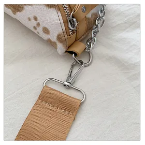 Nahaufnahme der modischen Kuhmuster Umhängetasche mit Metallkette und breitem Gurt.