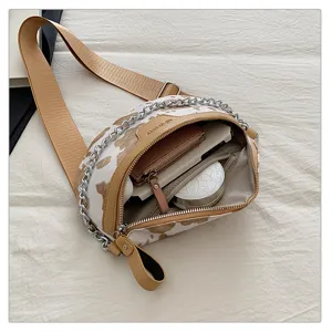 Detailansicht der modischen Damen Brusttasche mit Kuhmuster, breitem Gurt und Metallkette.