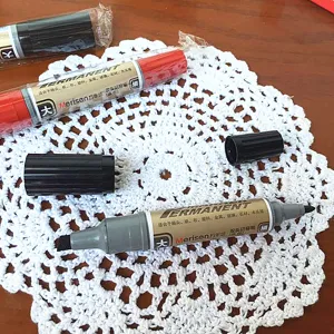 Primer plano del rotulador permanente de doble punta con tinta a aceite para varias superficies.