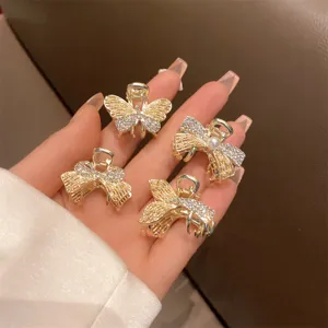 Dettaglio in primo piano di piccole mollette per capelli con farfalla strass, clip dorata.