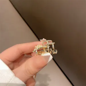 Dettaglio del fermaglio per capelli dorato con perle e strass per frangia e lati.
