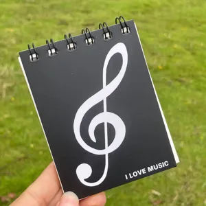 Primo piano dettagliato di un taccuino a spirale A7 nero con copertina di nota musicale.