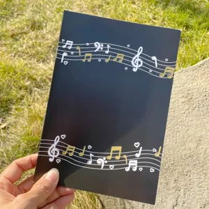 A5 Notizbuch mit Musiknoten, schwarzem Einband und goldenem Notensystem Design.