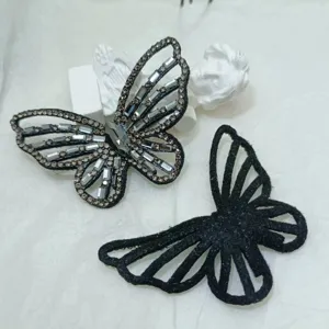Close-up detail of DIY crystal rhinestone butterfly accessory and black fabric patch for clothing.