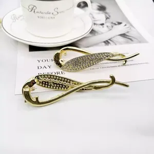 Vue détaillée de la pince à cheveux dorée strass, design élégant queue de poisson.