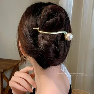 Élégante pince à cheveux dorée en métal avec perle pour coiffures et chignons chics.