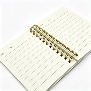 Primo piano del quaderno a spirale con anelli doppi dorati e pagine rigate.