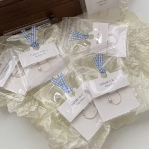 Gros plan détaillé de bagues délicates emballées dans des sachets avec cartes à ruban.