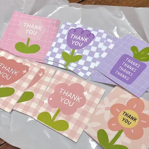 Close-up detail of mini square thank you cards with cute floral patterns and English text.