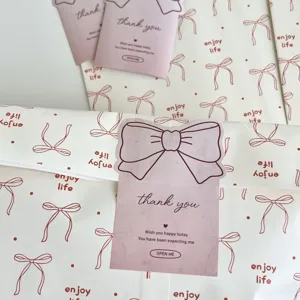 Detailed view of aesthetic kraft paper gift bags with cute bow prints and thank you cards for gifts.