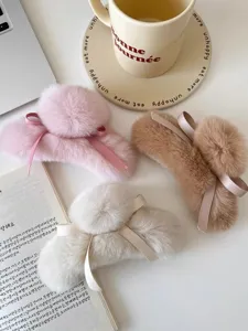 Détail de pince à cheveux en peluche douce, avec joli nœud ruban et design pompon charmant.