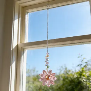 Detail view of the pink crystal flower suncatcher hanging near the window with bright lighting.