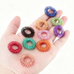 Primer plano de anillos de masaje para dedos de resorte metálico colorido, antiestrés