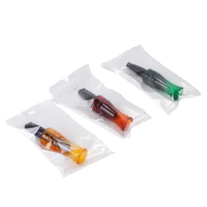 Detail view of colorful plastic crow hunting whistles in transparent bags for outdoor sports.