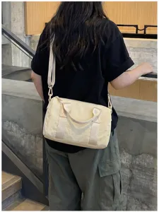 Gedetailleerd overzicht van een beige Boston handtas voor dames met handvatten en riem.