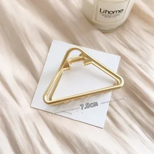 Primo piano della molletta per capelli a triangolo dorato con finitura in lega di metallo.