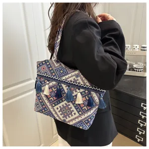 Ethnic style woven tassel tote bag detail shot, vintage geometric pattern shoulder handbag.