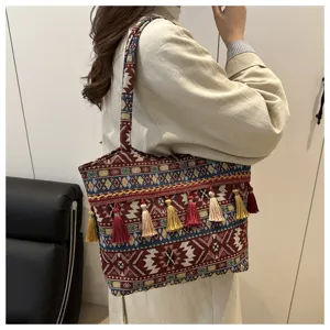 Ethnic style woven striped tote bag with colorful tassels, fashionable shoulder handbag for travel.