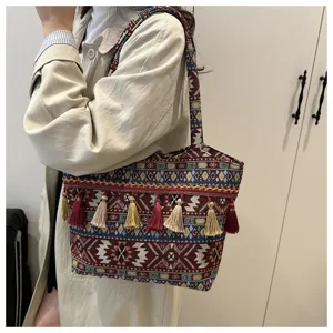 Detail shot of ethnic style woven shoulder bag with colorful tassels and geometric patterns.