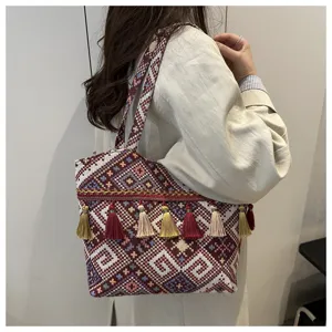 Ethnic style woven tote bag detail with geometric patterns, colorful tassels and strap.