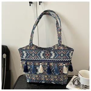 Ethnic style woven tote bag detail, featuring decorative tassels and geometric pattern.