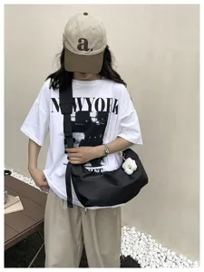 Detailed shot of black nylon underarm shoulder bag worn in casual daily street style.