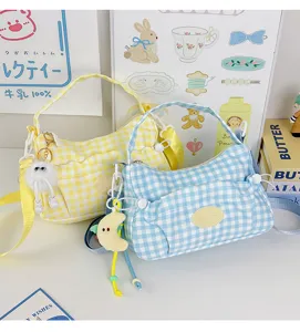 Detailed view of trendy plaid shoulder bag with cute charms and front pocket design.