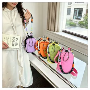 Detail shot of mini crossbody bag with colorful woven strap and front pocket outdoor scene setup
