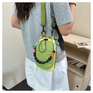 Detail view of the green and yellow mini crossbody phone bag featuring a colorful braided handle.