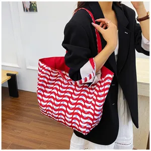 Detailed shot of a stylish red and white wave print large capacity fabric tote bag worn by model.