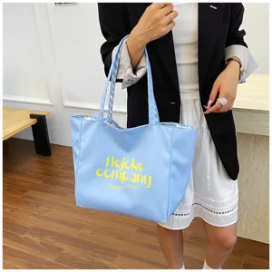 Detailed view of the light blue nylon tote bag with stylish yellow graphic print and handles.