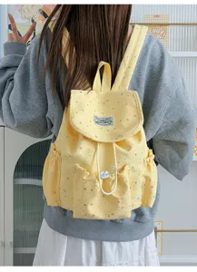 Detailaufnahme des gelben Rucksacks aus Leinen mit Sternen, Kordelzug und Vordertasche.