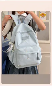 Detailed view of light blue student backpack with cute bow embroidery and multiple storage pockets.