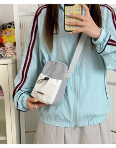 Pequeño bolso bandolera para móvil con diseño bicolor, correa ajustable y bolsillo delantero.