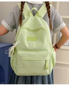 Detailed view of the cute light green backpack with bow embroidery and front badge for girls.