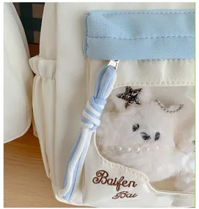 Klare Detailansicht der Rucksack-Vorderentasche mit süßer Plüschpuppe und Stickerei.