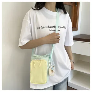 Detail view of the colorful dopamine phone crossbody bag with drawstring and plush pendant.