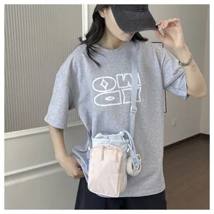 Close-up detail of the colorful crossbody phone bag showing zipper pocket and cute plush charm.