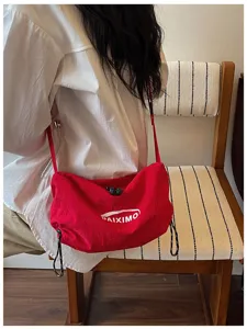 Vista ravvicinata della borsa a tracolla rossa in nylon con dettagli di tessitura e coulisse.