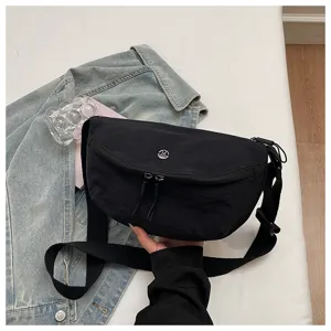 Close-up detail of a black casual crescent shoulder bag with double zipper and strap.