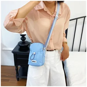 Detailed view of casual light blue crossbody phone bag worn by model, showcasing strap and design.