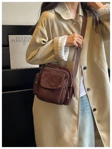Vue détaillée d'un sac bandoulière marron en velours côtelé aux multiples poches pratiques.