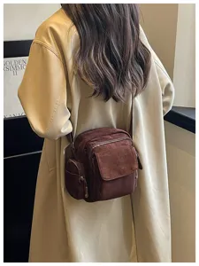 Vue détaillée du sac bandoulière en suédine marron porté au dos dans un style sportif.