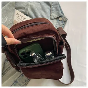 Vue détaillée du sac bandoulière marron en velours côtelé montrant le rangement intérieur.