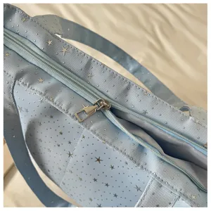 Light blue star print shoulder bag detail showing textured fabric and metal zipper.