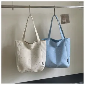 Canvas tote bag detail showing star pattern, dual color options, and convenient front pocket design.