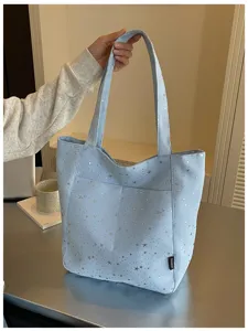 Detailed view of a light blue tote bag featuring silver star patterns and front pocket design.